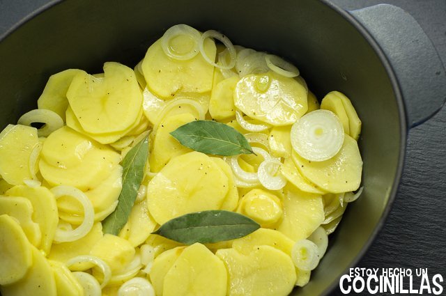Patatas y cebollas en una olla apta para horno