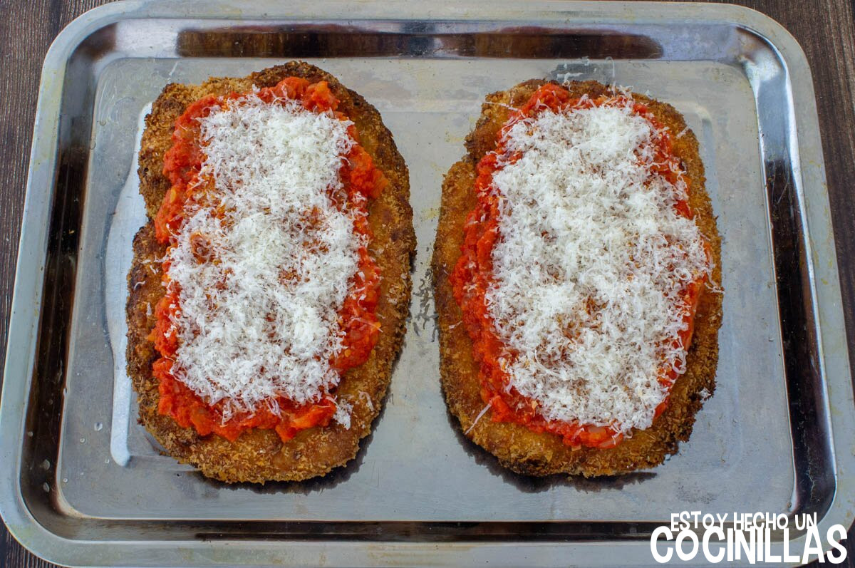 Espolvorear parmesano en las milanesas a la pizza