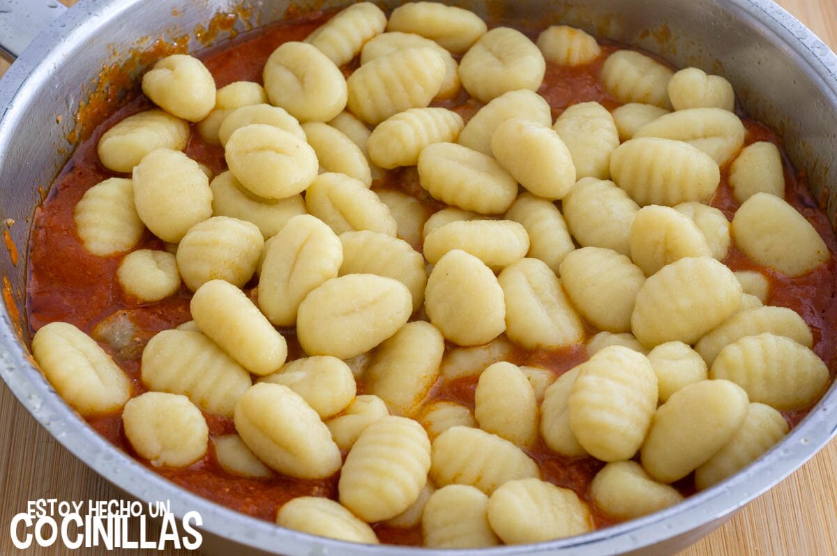 Integrar los ñoquis a la salsa con salchichas